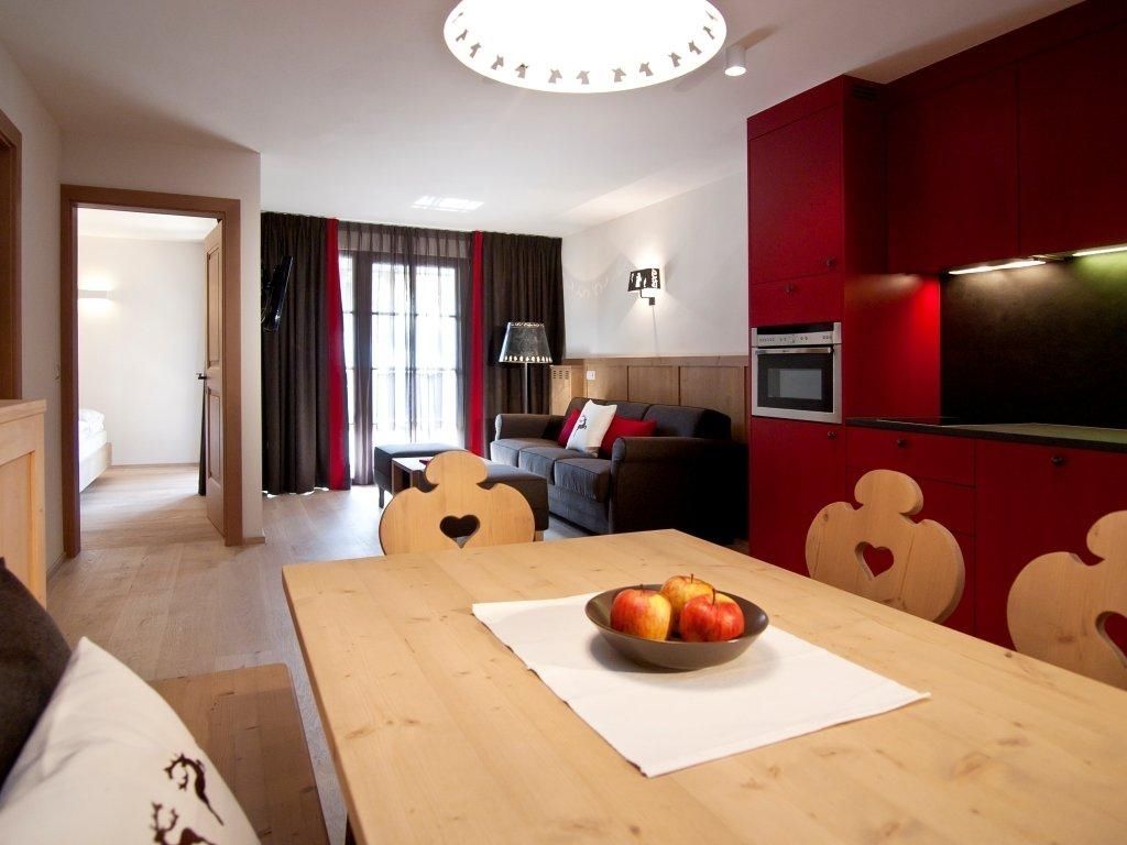 A modern living room with a wooden dining table, a bowl of fruit, and heart-shaped chairs.