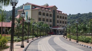 Un hotel con un camino de entrada curvo, palmeras y un edificio de techo rojo.