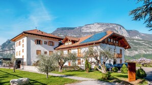 A two-story building with a sloped roof, solar panels, and a mountain backdrop.