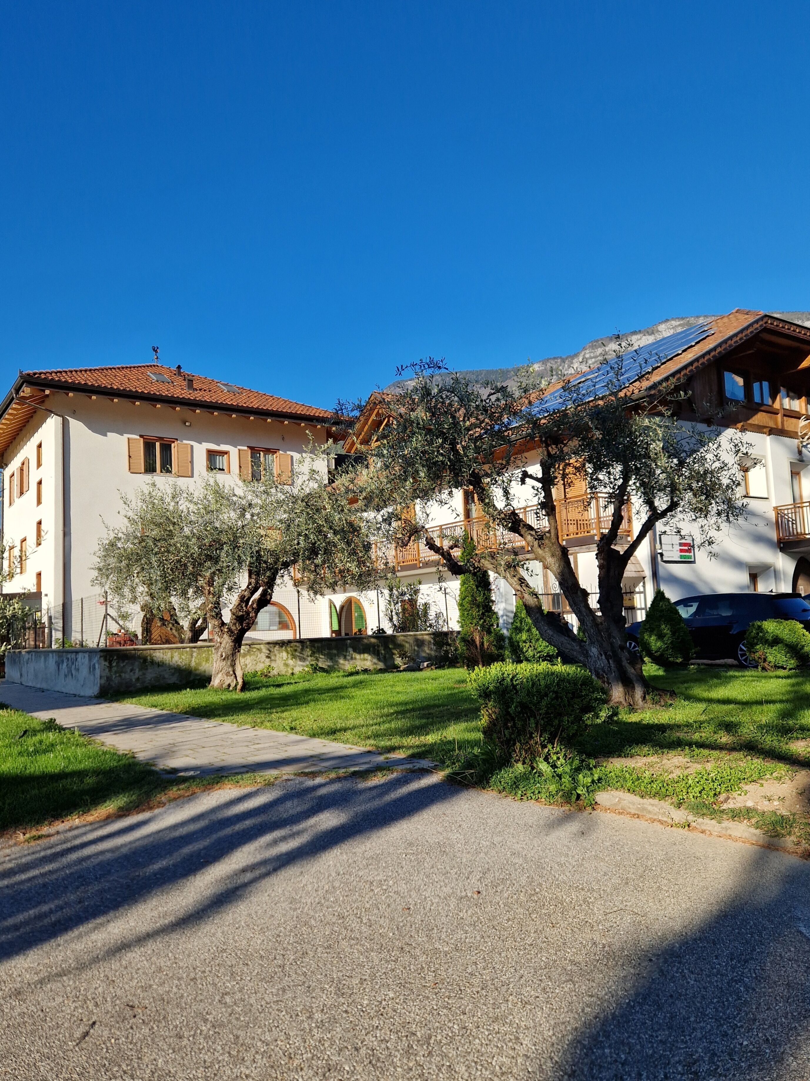 Un bâtiment traditionnel avec un toit en tuiles, entouré de pelouses et d’arbres bien entretenus.