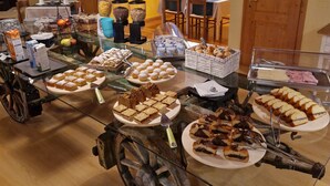 A buffet setup with various food items, wooden beams, and a rustic interior.