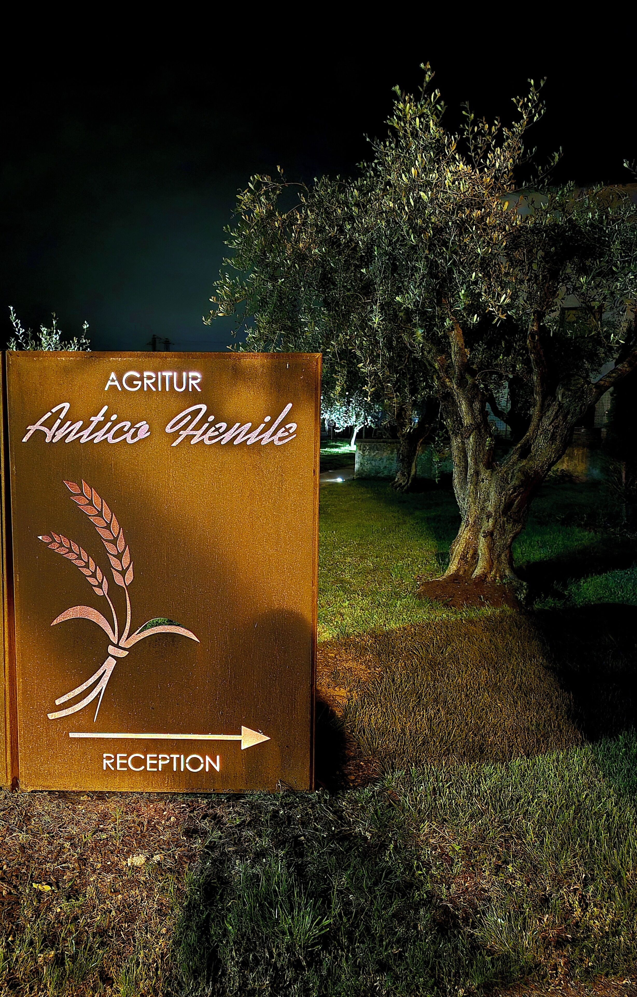 A reception sign for Agritur Antico Fienile with a wheat illustration and an arrow pointing right.
