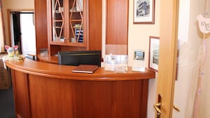 Un mostrador de recepción de madera con una silla negra, una vitrina de vidrio y cuadros en la pared.