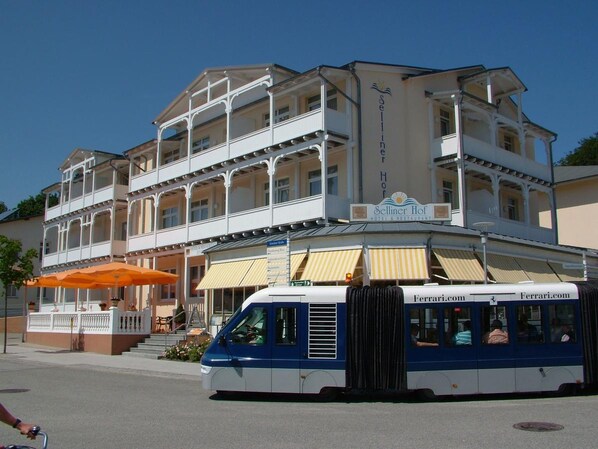 A two-story hotel with balconies and a Ferrari.com bus in front. - Hotel Selliner Hof (Sellin)