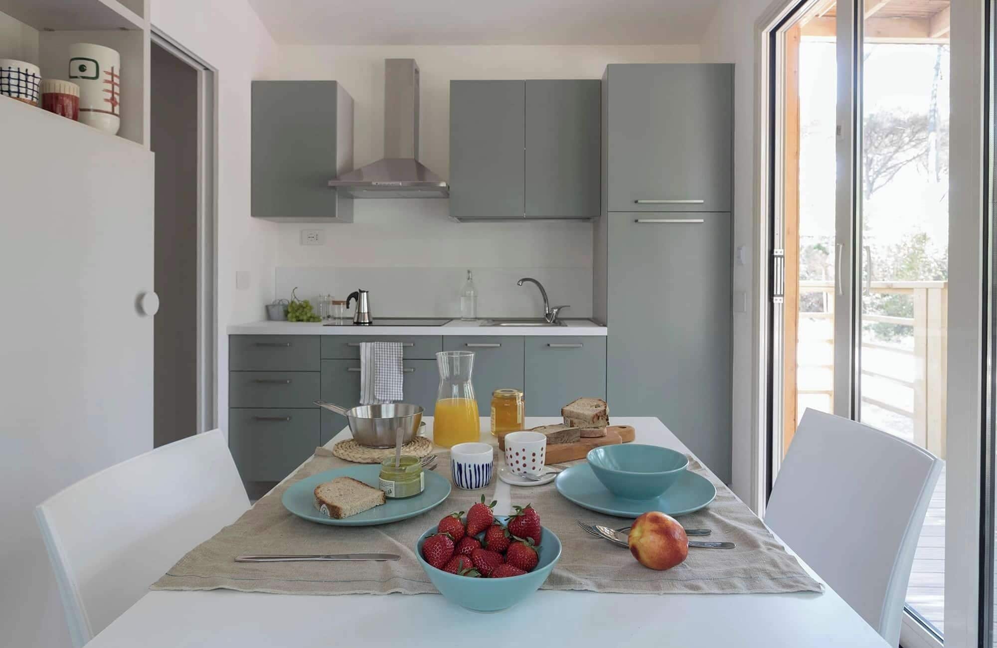 Una cocina moderna con armarios grises, una campana extractora de acero inoxidable y un ventanal con vistas a un balcón.