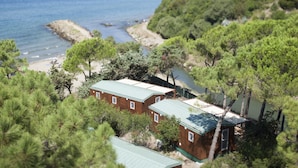 Uma propriedade costeira com várias cabanas de madeira, uma praia e um litoral rochoso.