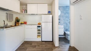 Uma cozinha compacta com armários brancos, forno embutido e um pequeno balcão.