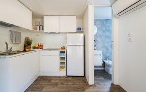 A compact kitchen with white cabinets, a built-in oven, and a small countertop. - PuntAla Camp & Resort (Castiglione della Pescaia)