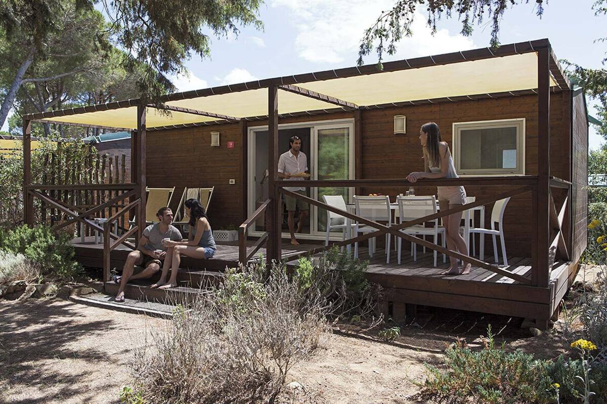 Een houten vakantiehuisje met een terras, buitenmeubels en een overdekte patio.