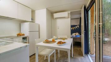 A compact kitchen with a dining area, a refrigerator, and a table set with food and drinks.