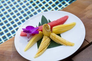A plate with sliced fruits and a flower on a table. - Bunwin Residence (Siem Reap)