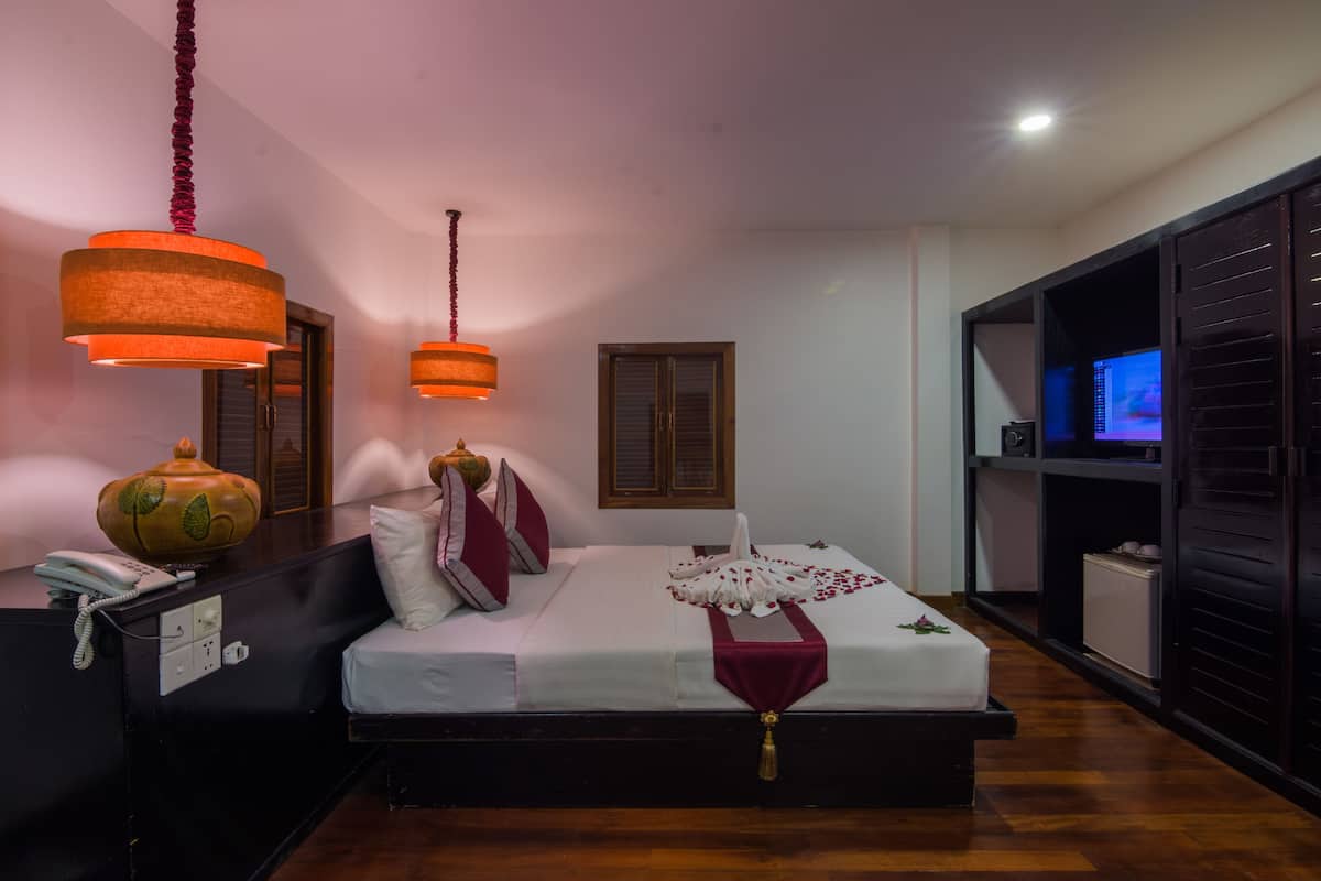 Un dormitorio ordenado con cama, mesita de noche y televisor.