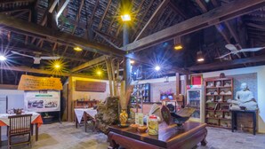A traditional interior with wooden beams, a central table, and a statue. - Bunwin Residence (Siem Reap)