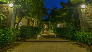 A well-lit pathway leading to a building with a brick facade, surrounded by lush greenery and a clear night sky. - Bunwin Residence (Siem Reap)