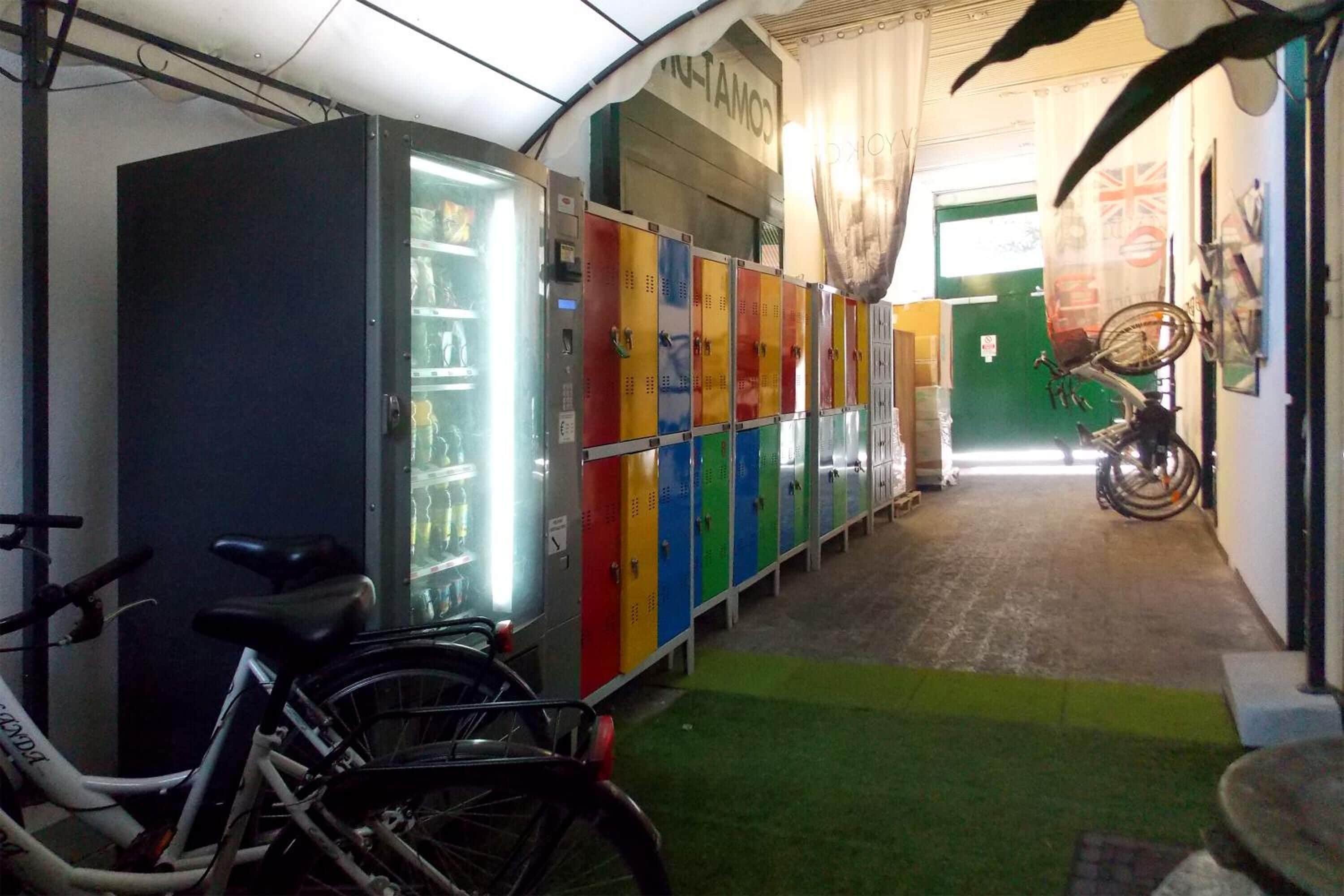 A corridor with lockers, a bicycle, and a refrigerator.