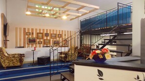 A multi-level interior with a staircase, wooden panel wall art, and a blue railing. - Hostel Colours (Milan)