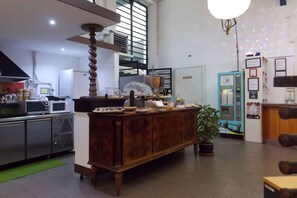 A kitchen with a wooden island, microwave, refrigerator, and a coffee machine. - Hostel Colours (Milan)