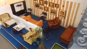 A room with a blue carpet, a white sofa, a brown armchair, and a wooden-framed picture wall. - Hostel Colours (Milan)