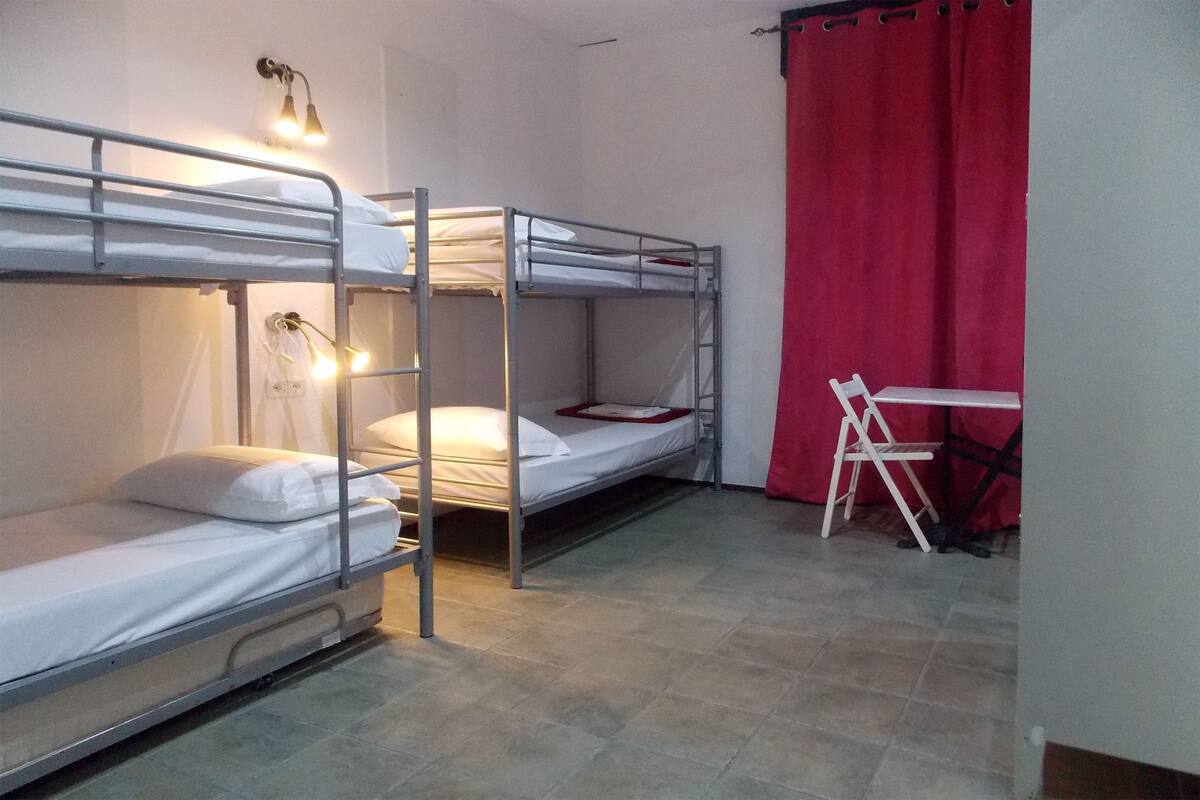 Un dormitorio con literas, un escritorio y una cortina roja.