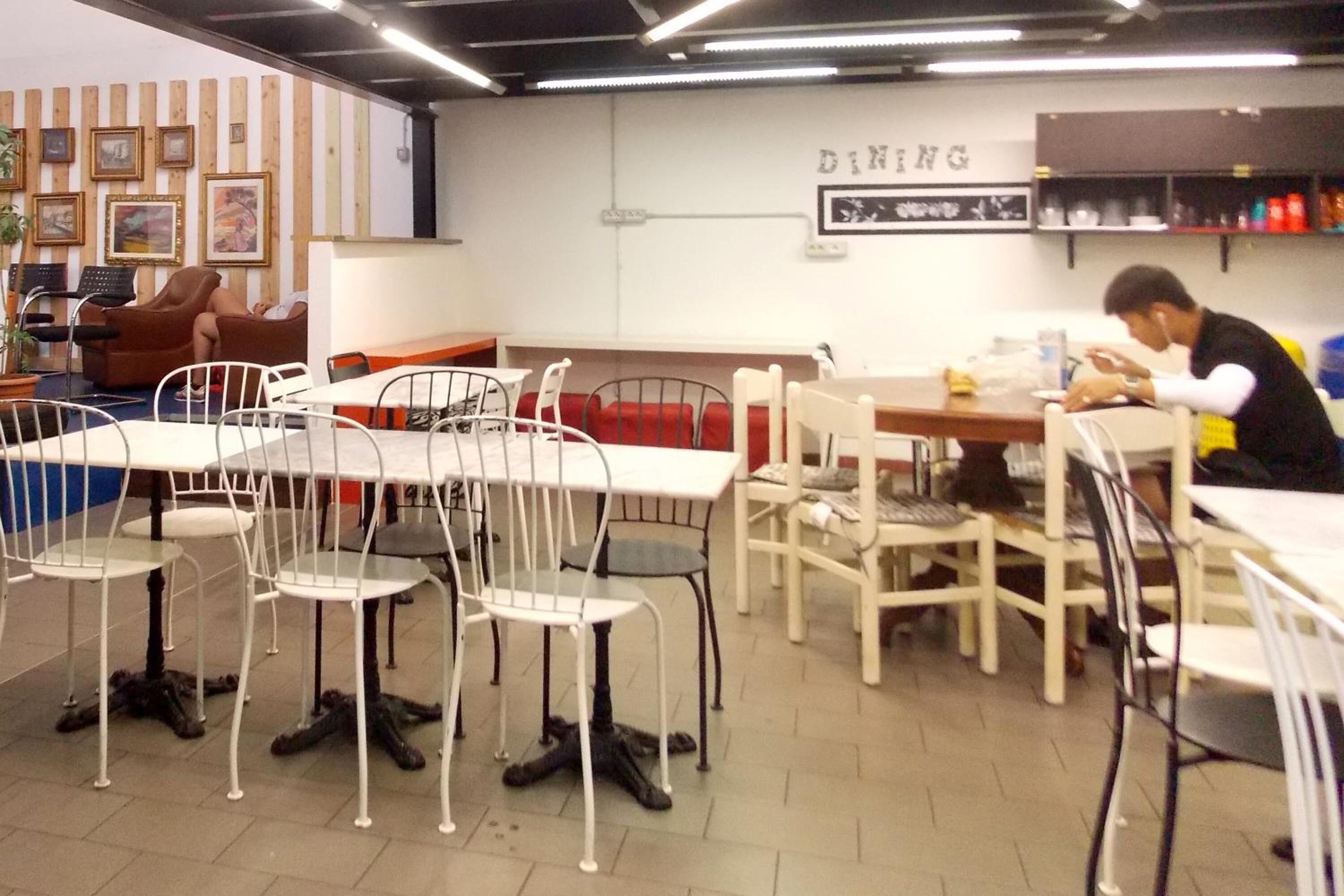 Un espace repas avec des tables et des chaises, un canapé et un mur orné de tableaux.