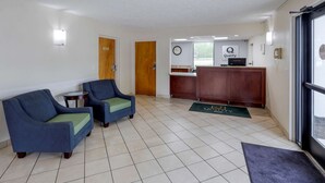 A reception area with a desk, two armchairs, a clock, and a sign that says "Quality". - Quality Inn - Roxboro South (Roxboro)