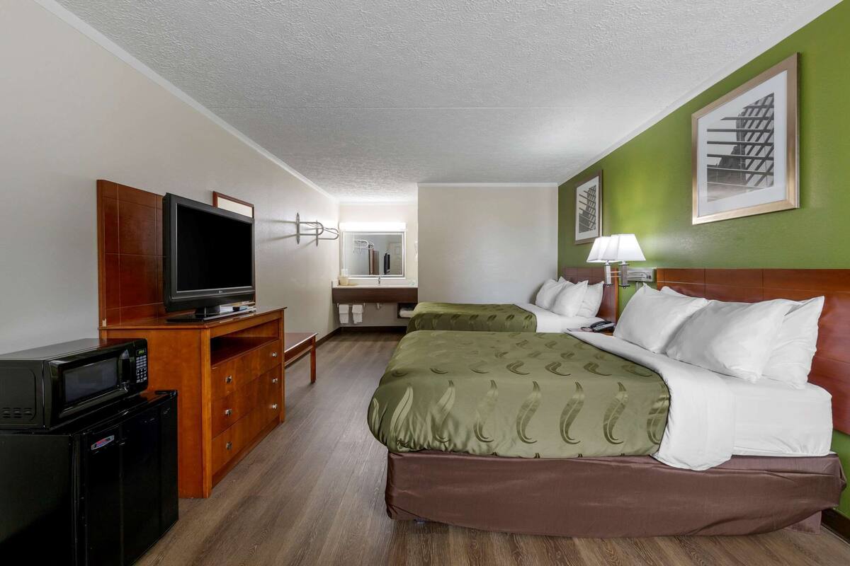 A hotel room with a bed, a TV, a desk, and a mirror.