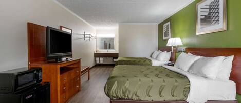 Una habitación de hotel con cama, televisión, escritorio y espejo.
