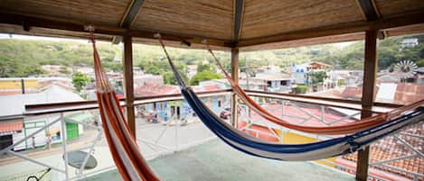 A hammock in a covered outdoor area with a view of buildings and a windmill in the background.