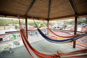 Una hamaca en un espacio exterior cubierto con vista a edificios y un molino de viento al fondo.