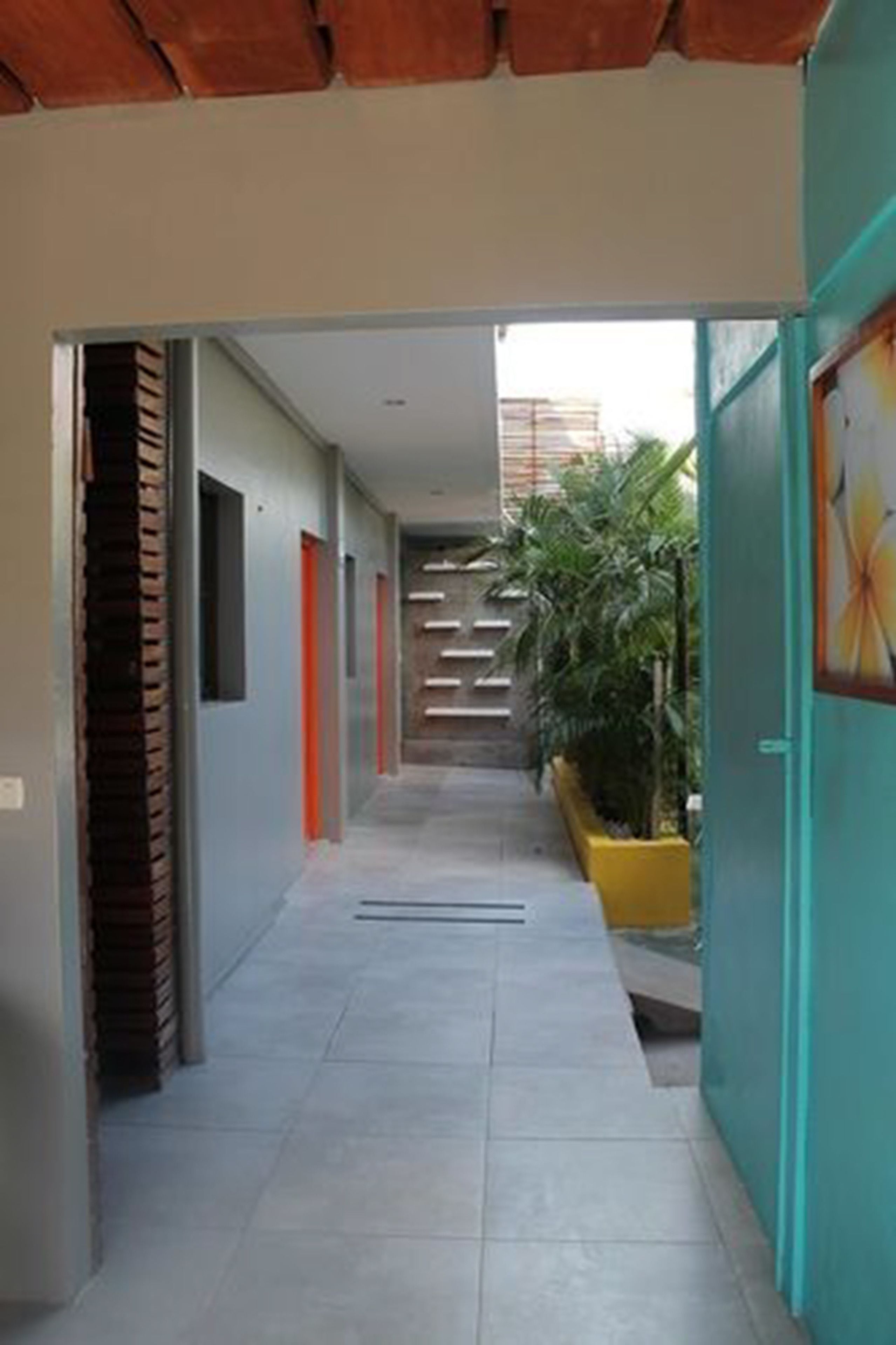 A corridor with a tiled floor, a staircase, and a planter with plants.