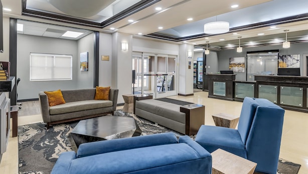 A modern lobby with a sofa, armchairs, a coffee table, and a reception desk. - Best Western Plus JFK Inn & Suites (North Little Rock)