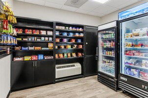 Zona de venta automática con varios estantes llenos de aperitivos y bebidas.