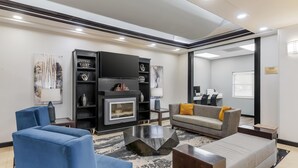 A modern living room with a fireplace, blue and grey sofas, and a coffee table. - Best Western Plus JFK Inn & Suites (North Little Rock)