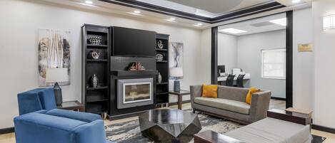 A modern living room with a fireplace, blue and grey sofas, and a coffee table.