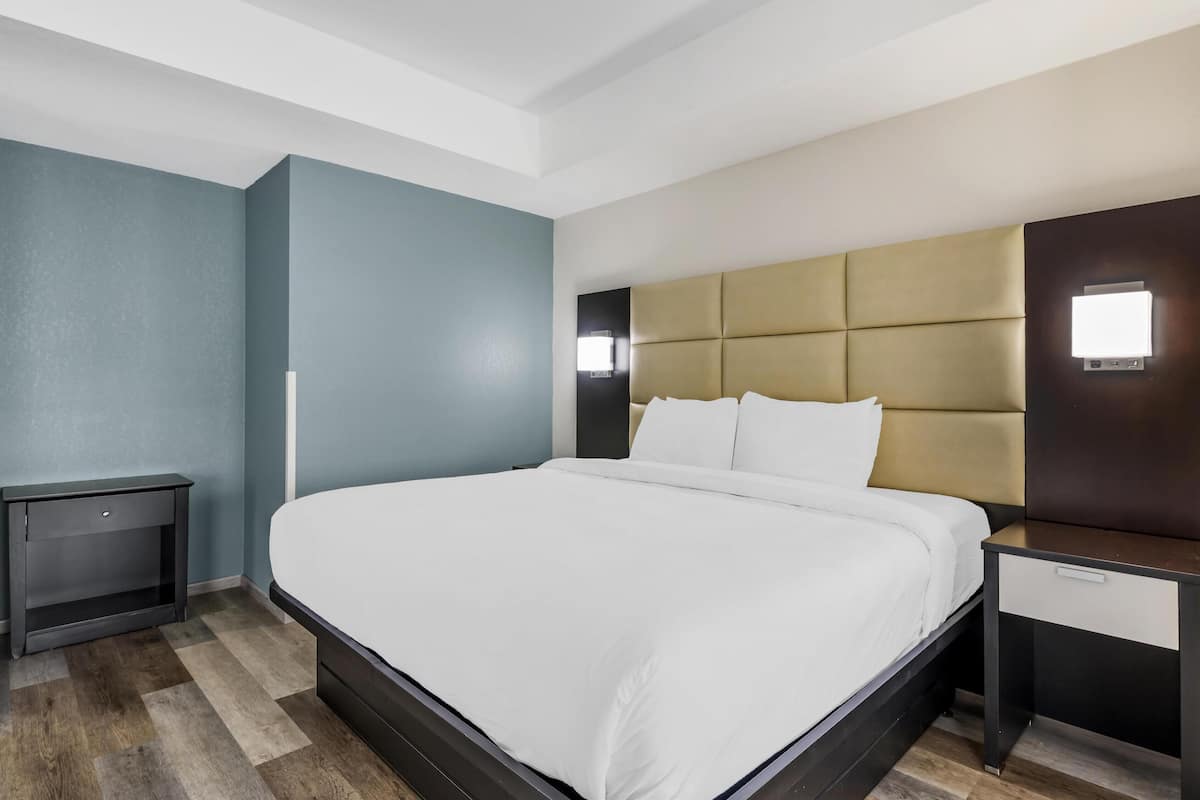A modern hotel room with a large bed, a bedside table, and a nightstand.