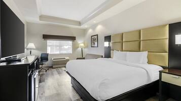 A modern hotel room with a large bed, a desk, and a chair.