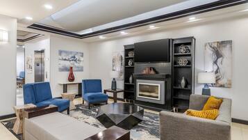 Una sala de estar moderna con chimenea, sofás azules y grises, y una mesa de centro.