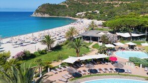 A resort with a pool, beach, and mountain views.