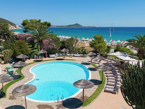 A resort pool area with a clear view of the sea, lounge chairs, and umbrellas. - Hotel Residence Cormoran (Villasimius)