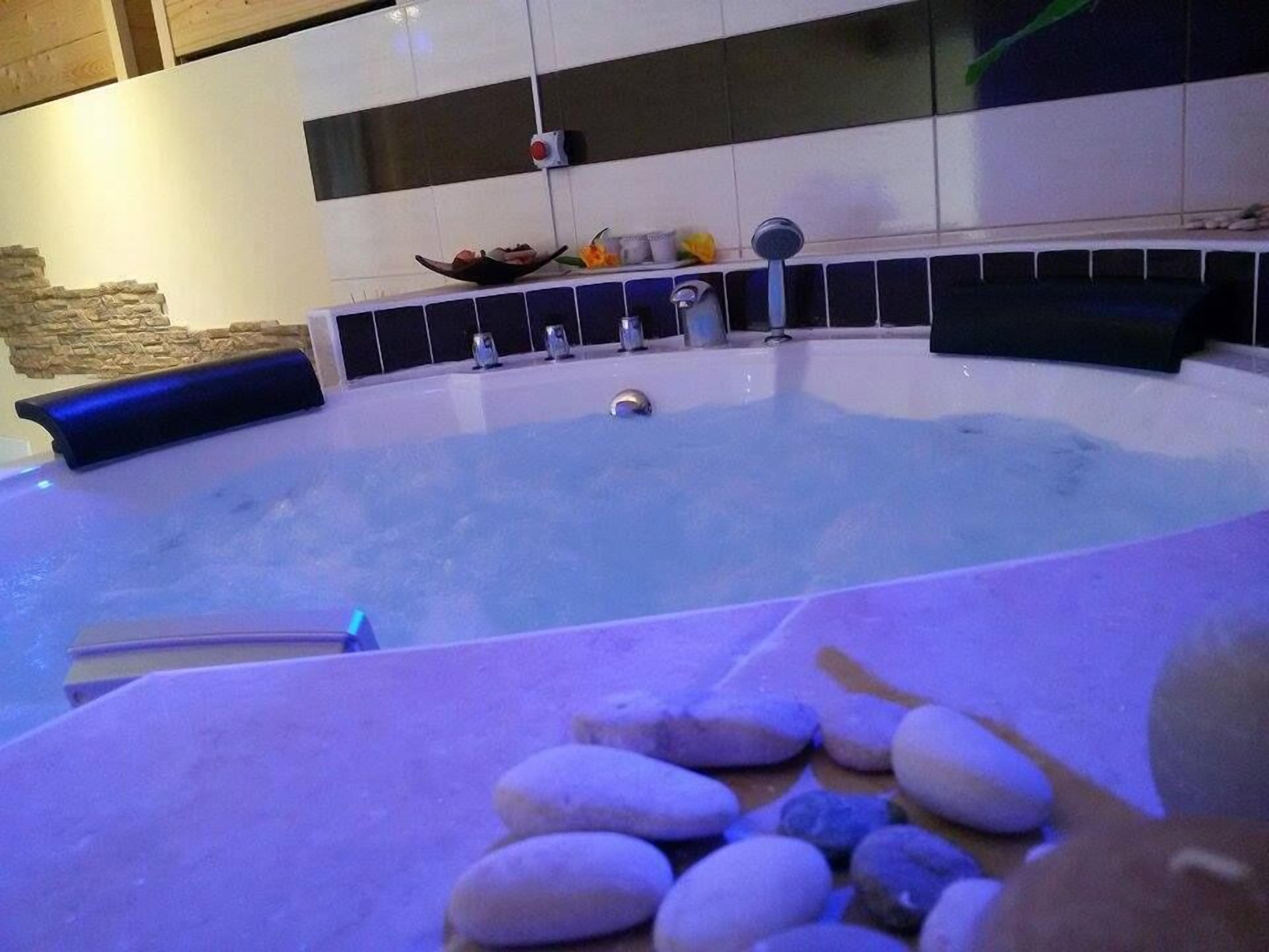 A modern spa area with a hot tub, a stone seating area, and a decorative wall with tiles and a stone accent wall.