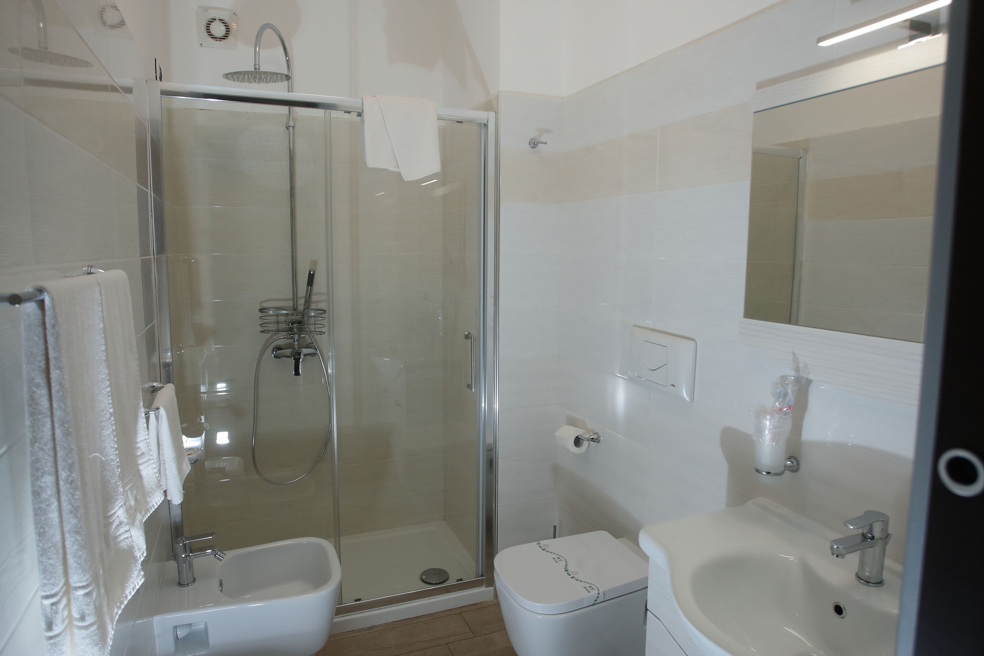 A bathroom with a glass-enclosed shower, a toilet, and a sink.
