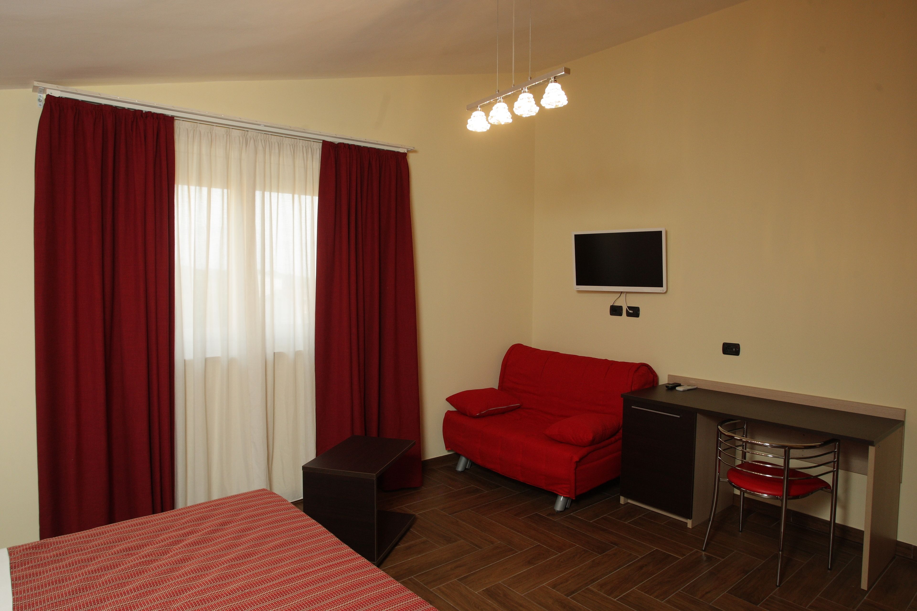 Ein Zimmer mit einem Bett, einem Schreibtisch, einem Sessel und einem Fernseher.