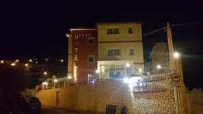 A hotel with a stone wall entrance, multiple floors, and a sign indicating a no parking zone. - Hotel Paradiso (Gizzeria)