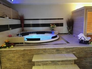 Un jacuzzi con pared de piedra y un banco en frente.