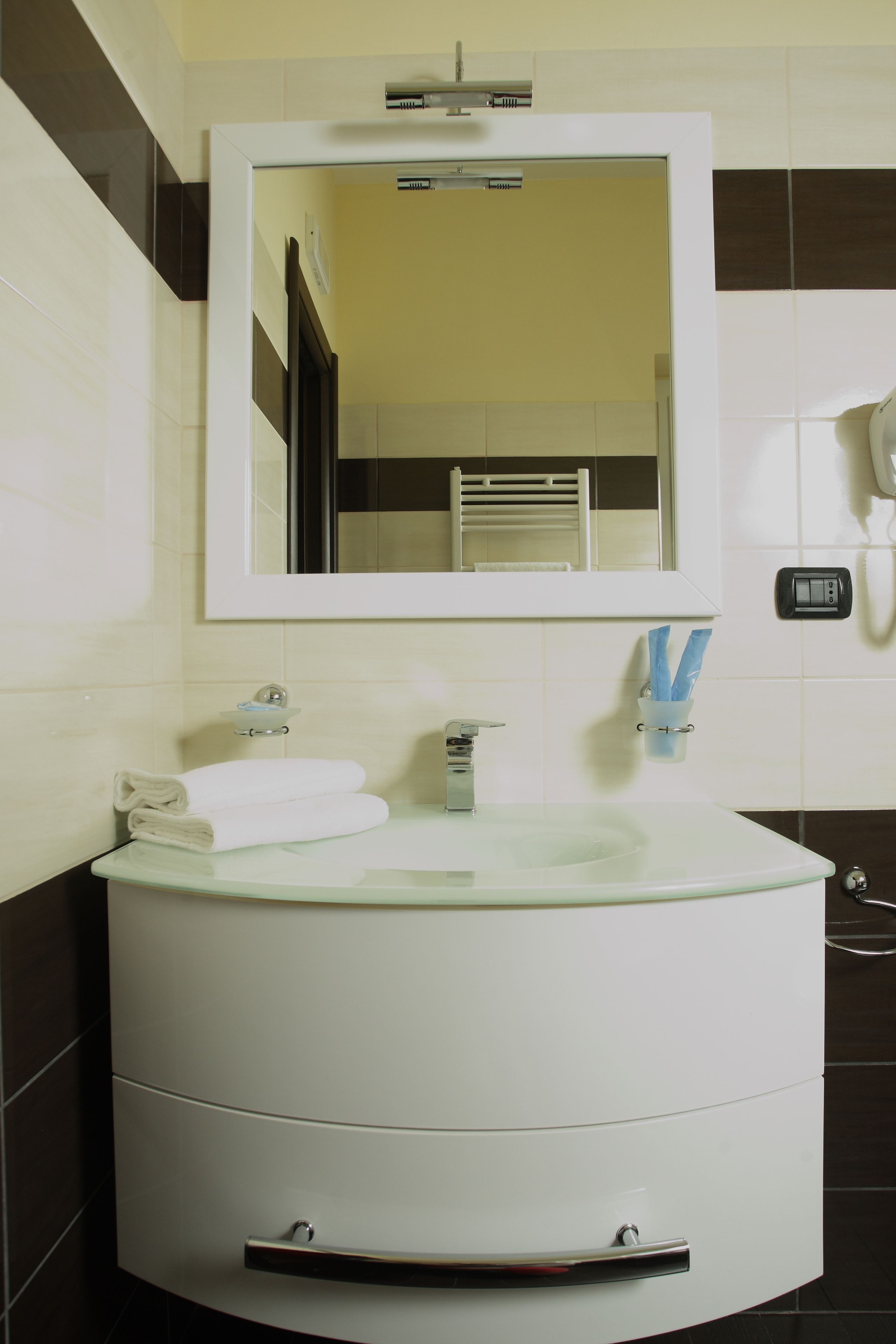 A bathroom with a white sink, a mirror, a towel rack, and a hairdryer.
