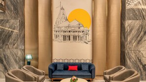 A lobby with a sofa, two armchairs, a coffee table, and a wall mural.