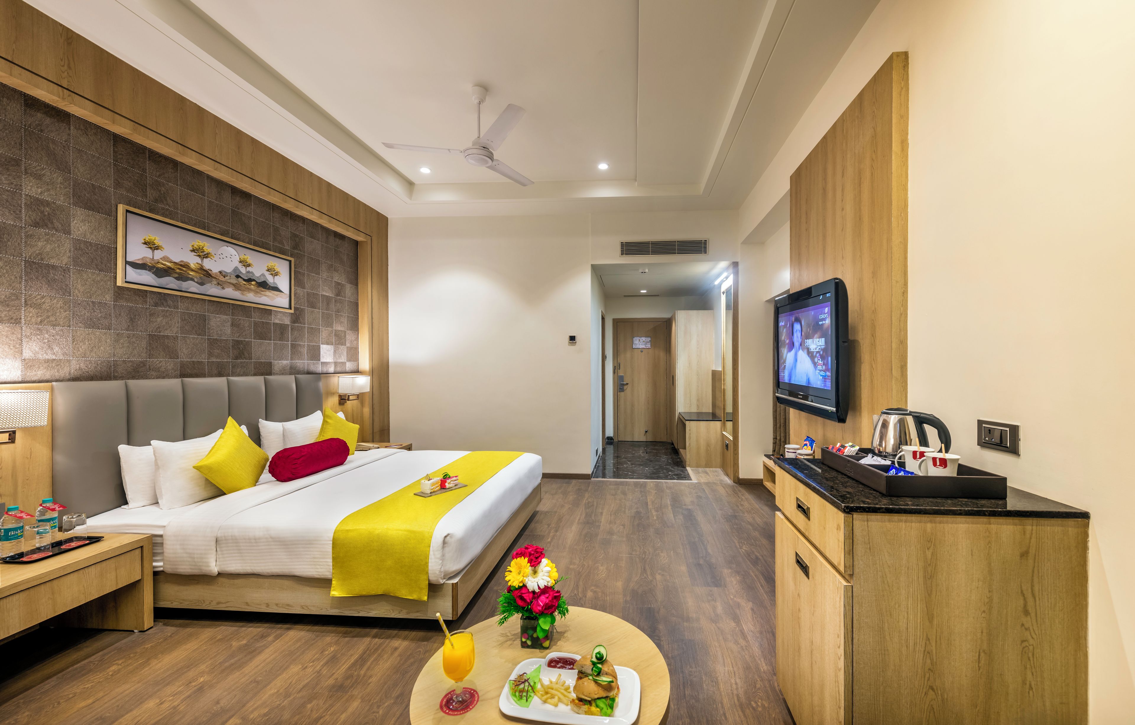 Ein Hotelzimmer mit Bett, Nachttisch, Fernseher und einer kleinen Essecke für zwei Personen.