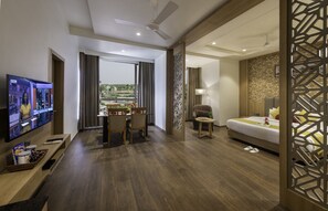 A hotel room with a dining area, a bed, a TV, and a view of the outdoors.