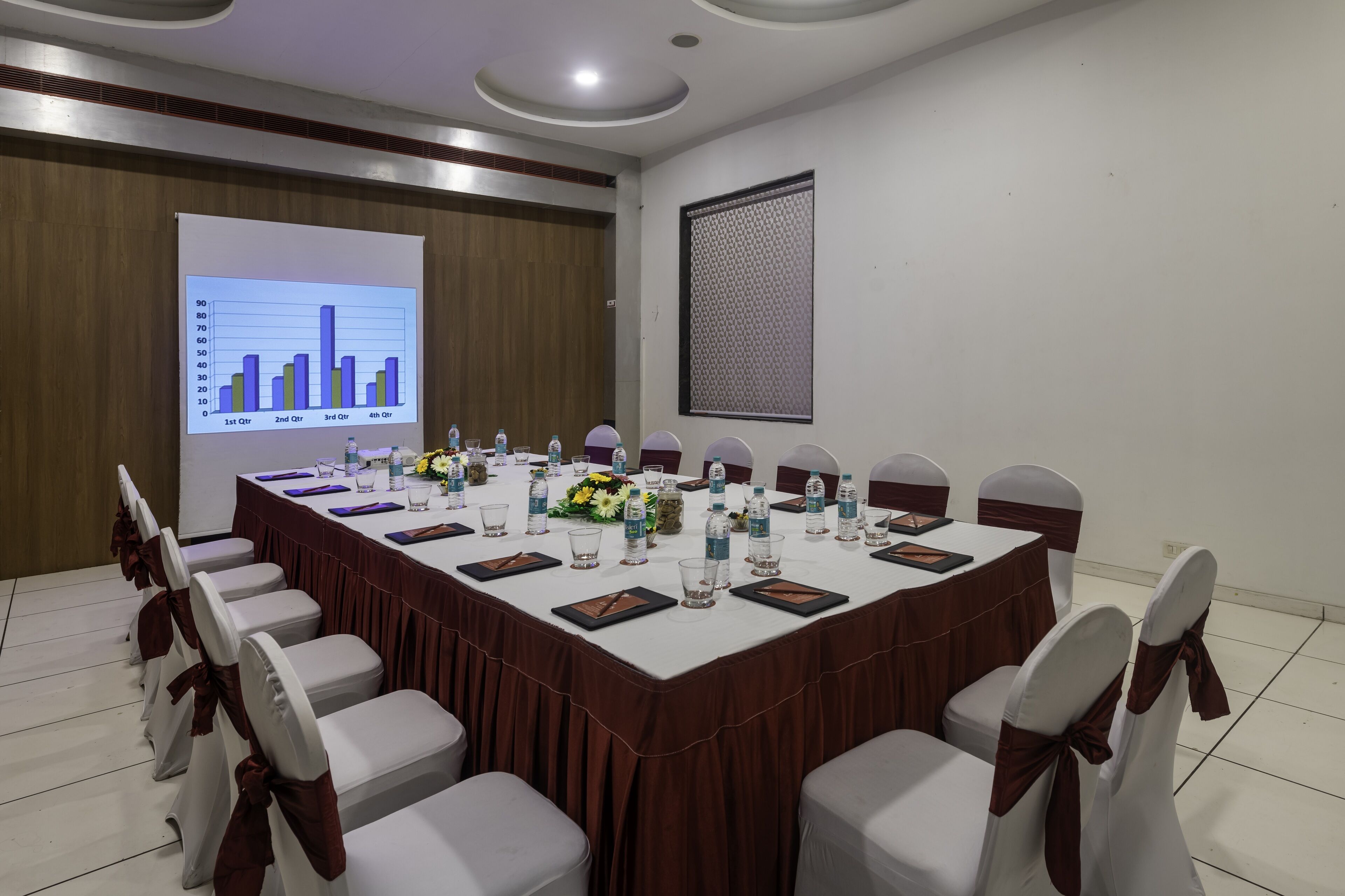 A conference room with a long table, chairs, and a presentation screen.