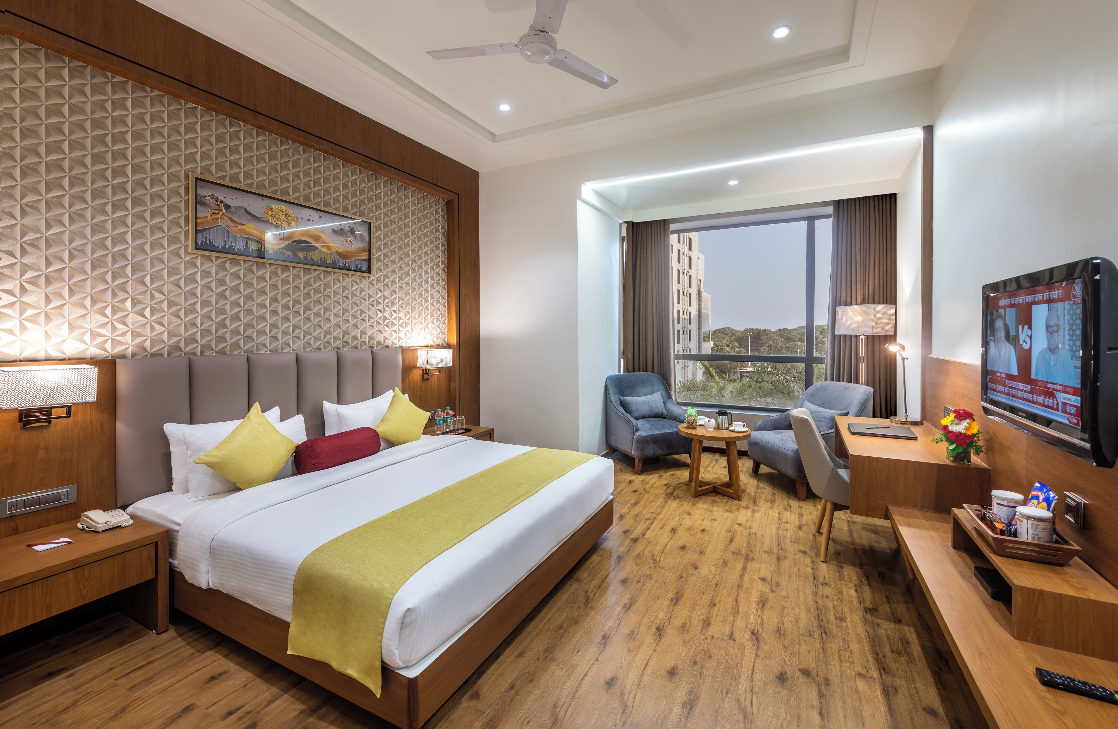 A hotel room with a bed, a desk, a chair, a television, and a window with a view.